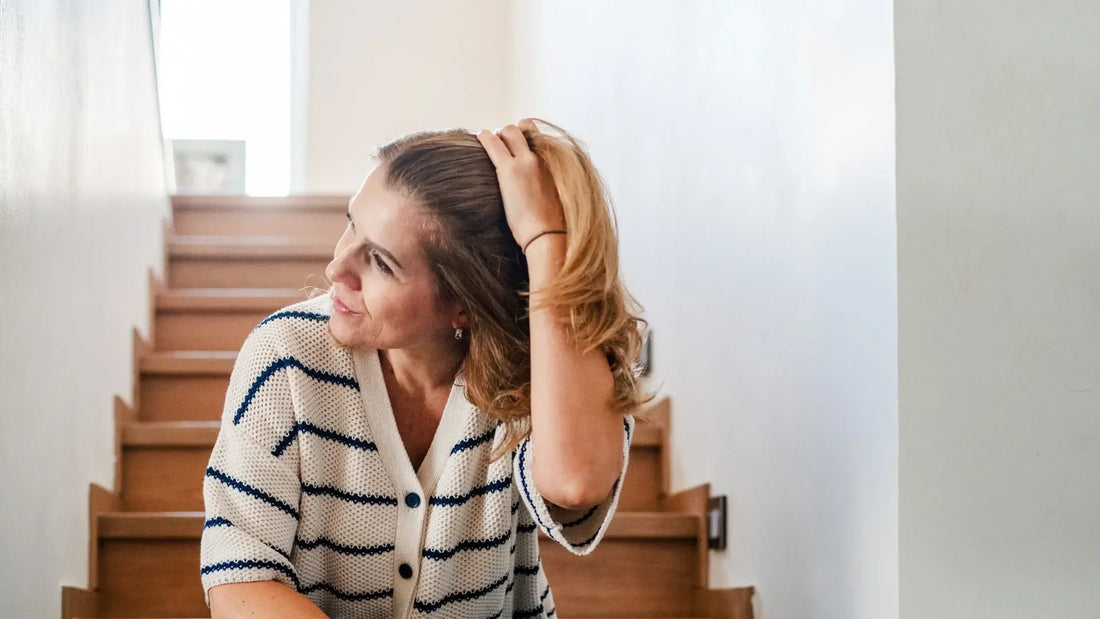 Woman sat on stairwell running hands through her hair